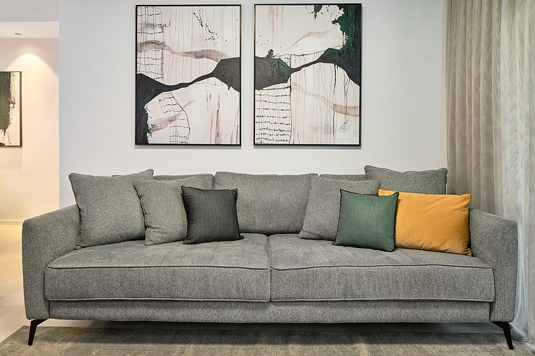 סלון מודרני בכפר סבא עם ספה אפורה, קיר טלוויזיה ירוק עם אחסון וספסל ישיבה, שולחן סלון, שטיח, ווילון רשת אפור.